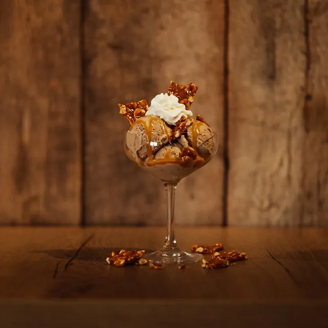 Brésilienne op de houten toog: mokka-ijs met karamel, nootjes en slagroom in een glazen coupe