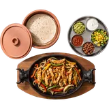 Fajitas Pollo van boven: reepjes kip met paprika en ajuin in de gietijzeren pan, met tortilla's en schaaltjes garnituur