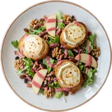 Salade chèvre van boven: gegratineerde geitenkaas op toast met noten, appel en sla op een wit bord
