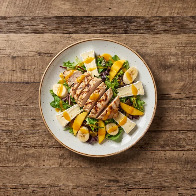 Salade Merimé van boven: gegrilde kip, brie, banaan en mango op gemengde sla