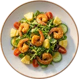 Salade scampi van boven: gemengde sla met scampi, ananas, tomaat en komkommer op een wit bord