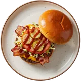 Smokey burger van boven met cheddar, gerookte bacon, sla, tomaat en augurk, het bovenste broodje ernaast