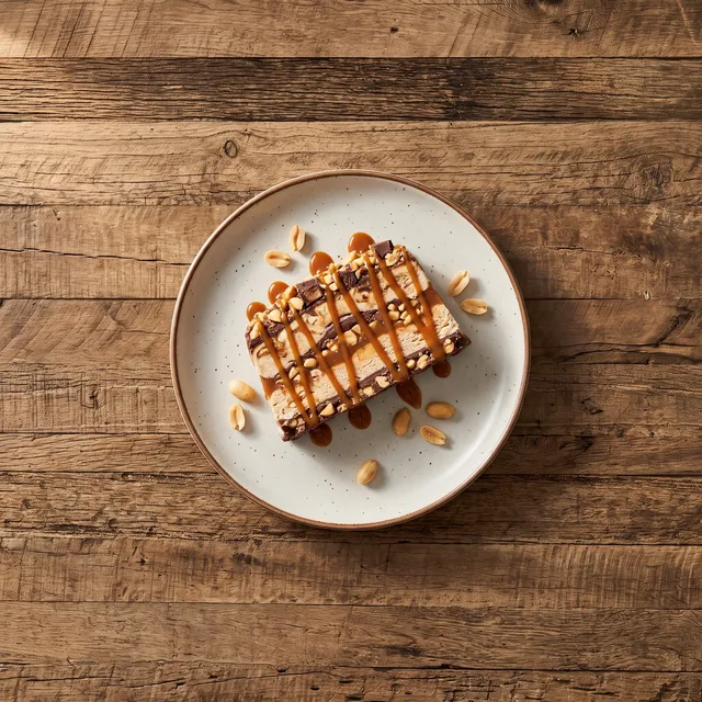 Huisgemaakte snickerparfait van boven met karamelsaus en pinda's