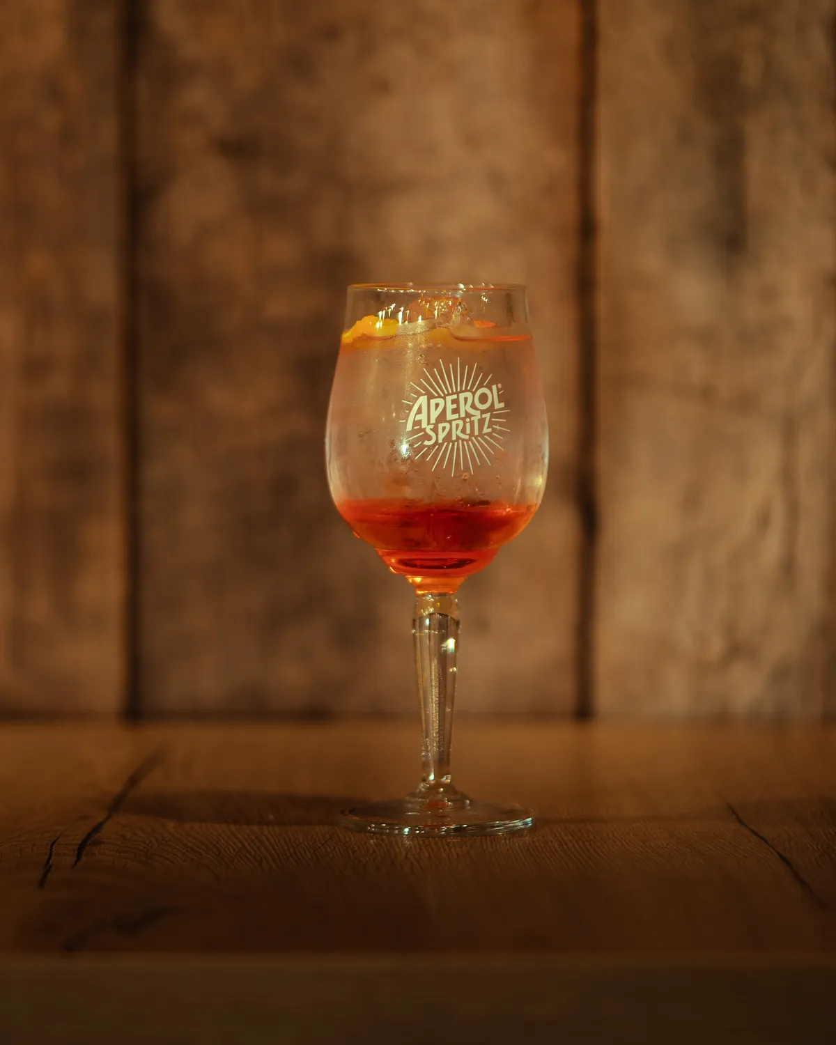 Aperol spritz op de houten toog van AXXES: oranje spritz in een wijnglas