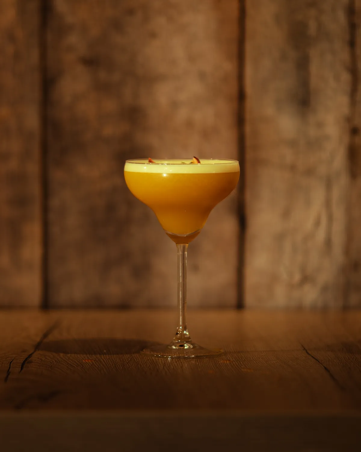 Pornstar Martini op de houten toog van AXXES: geeloranje cocktail in een coupeglas