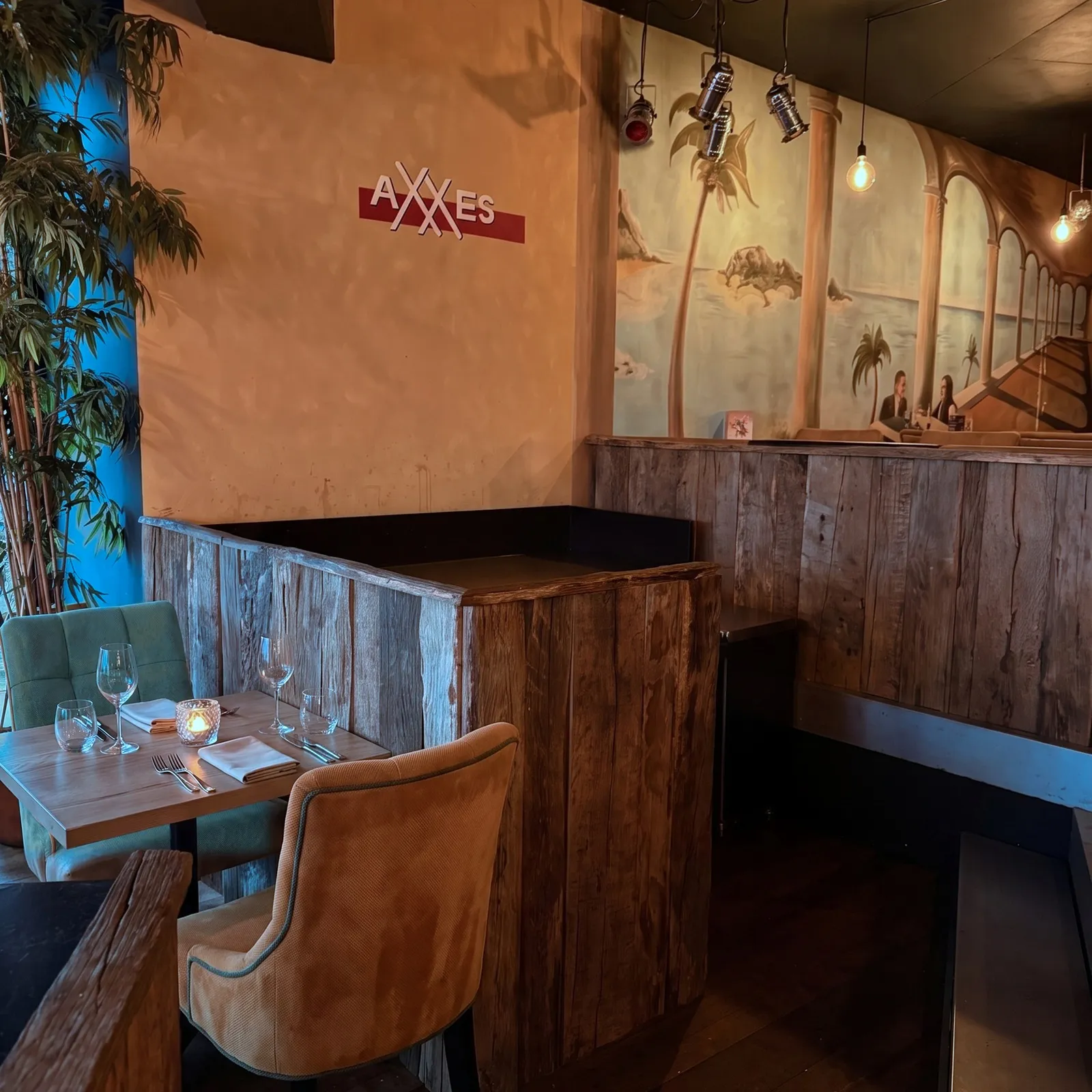 Tafel in de nis van AXXES met een oker stoel, barnhout en de muurschildering