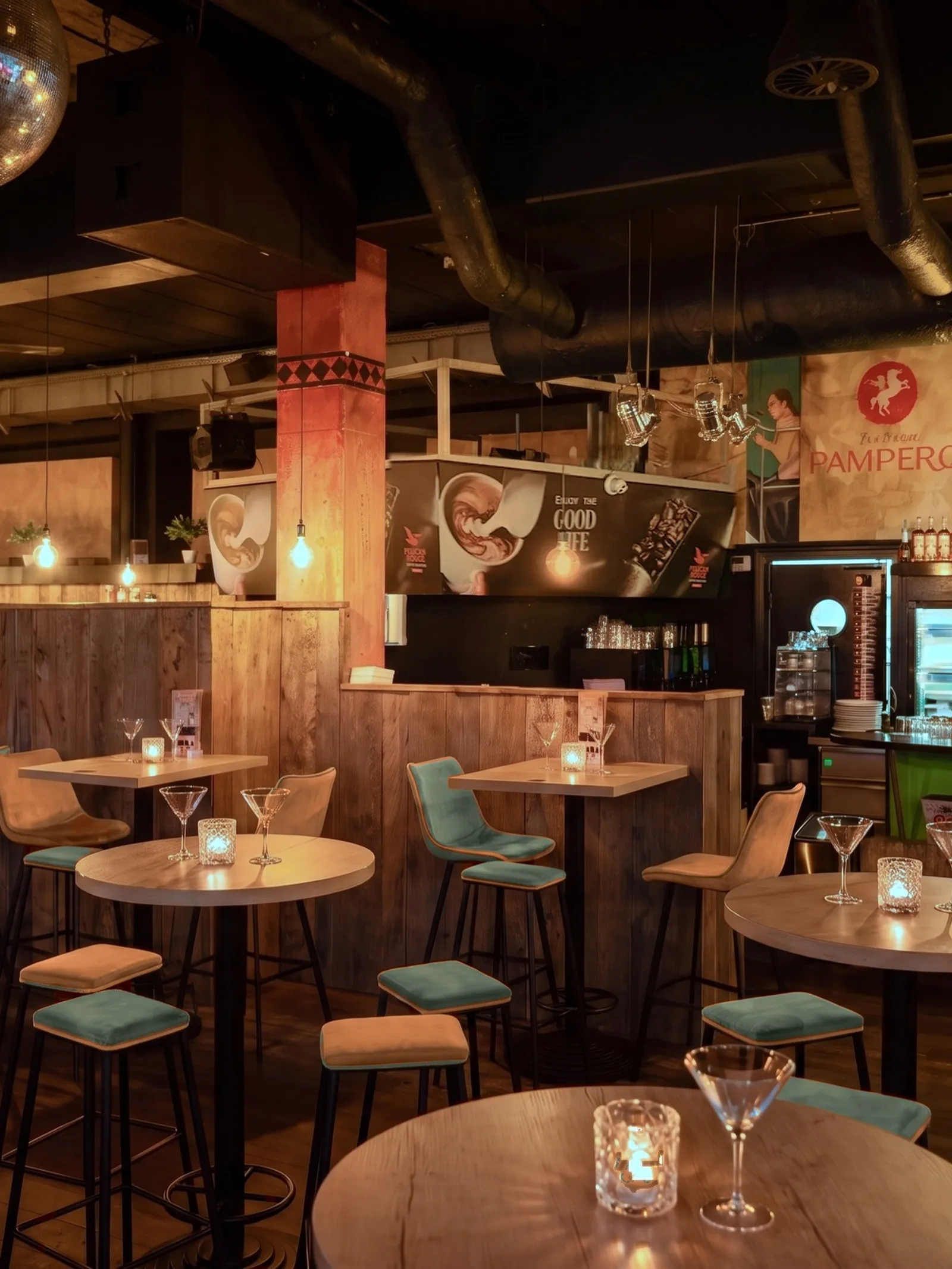 Hoge tafels en krukken bij de bar van AXXES bij avond